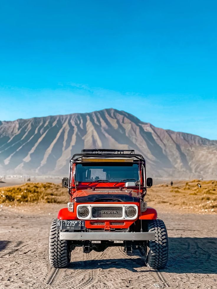 4WD jeep tour crossing the Sea of Sand at Mount Bromo with Mount Bromo and Mount Batok in the background during sunrise