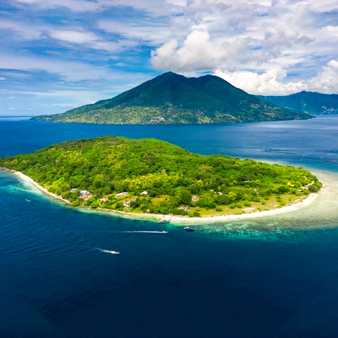 Kepa Island in Alor with crystal-clear blue waters, a coastal village, and lush green mountains in the background